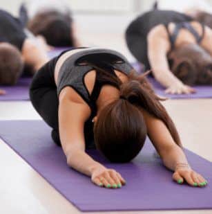 Woman laying on purple mat doing yoga