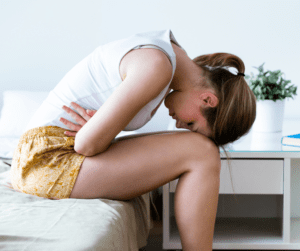 A woman bends over with bad cramps her menstruation or PMS is affecting her sleep.