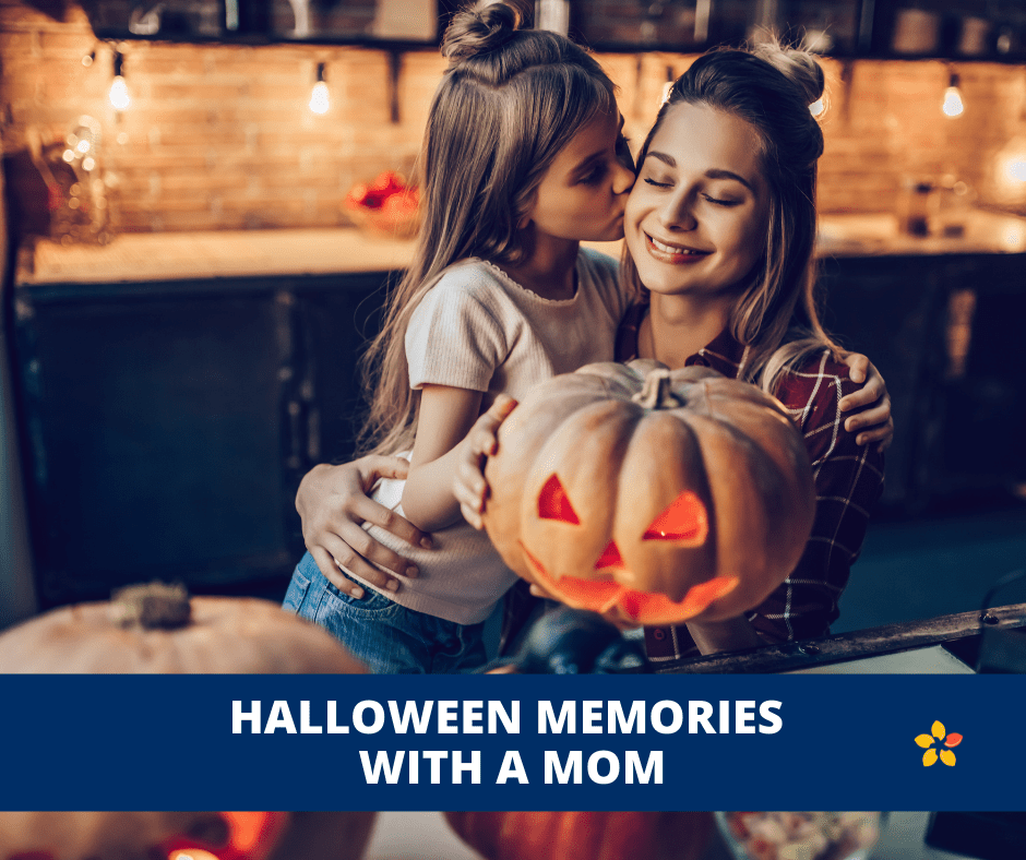 A mother and daughter light a candle for a Jack o Lantern.