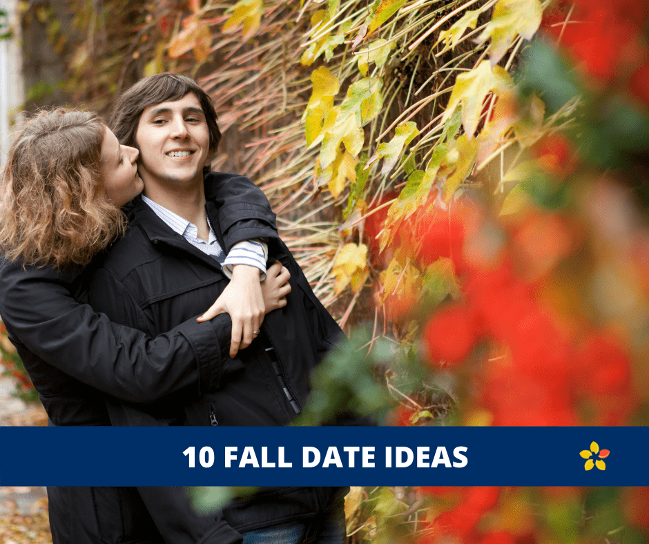 Two partners hug as they stand by fall leaves for some date ideas for the Fall.