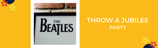A poster with the Beatles logo hangs on a brick wall, throw your own party in honor of the Queens Platinum Jubilee!