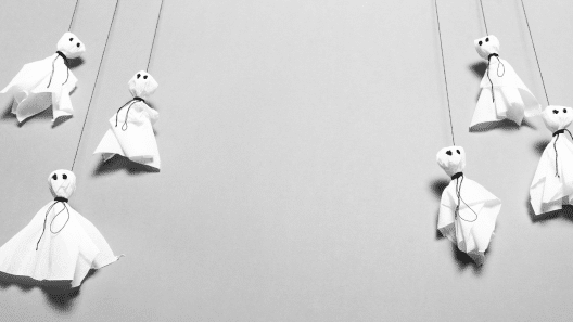 Ghosts made out of white cloth and black marker eyes hang on a string from the ceiling.